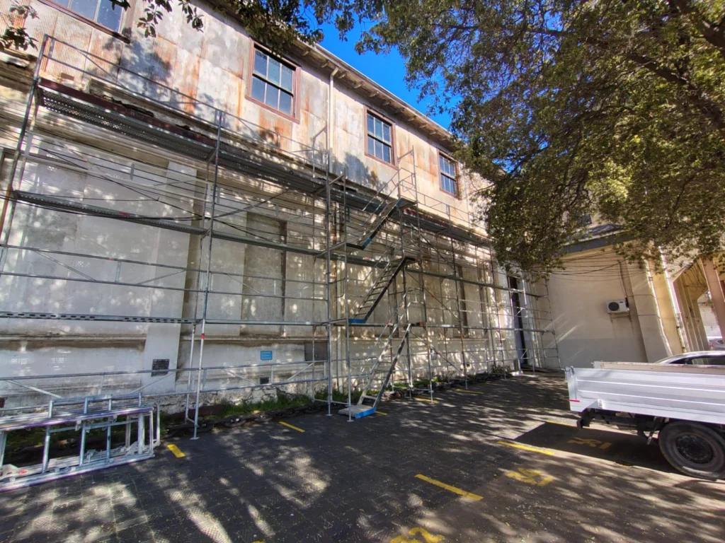 Andamio de fachada de dos niveles con escalera de acceso en un edificio